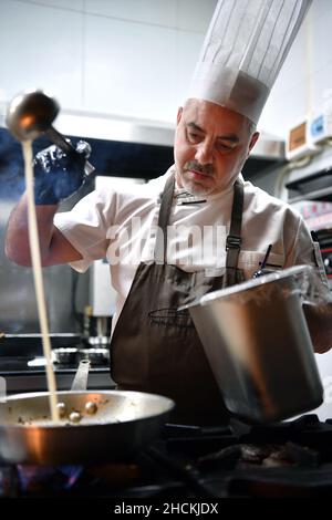 Sanya, la provincia cinese di Hainan. 28th Dic 2021. Daniele, proprietario e chef di un ristorante italiano, cucina al ristorante di Sanya, nella provincia di Hainan, nel sud della Cina, 28 dicembre 2021. PER ANDARE CON 'Profilo: Lo chef italiano compie sogno in Cina isola resort ' Credit: Guo Cheng/Xinhua/Alamy Live News Foto Stock