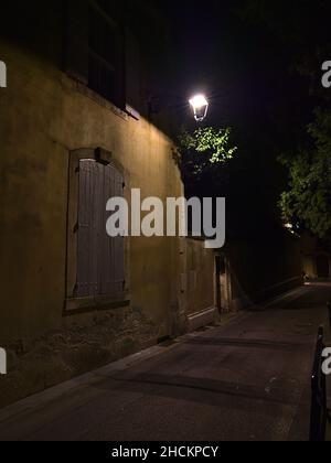 Vicolo stretto con alberi nel centro storico della città Arles nella regione della Provenza, Francia con lampada da strada e finestra chiusa di un edificio tradizionale. Foto Stock