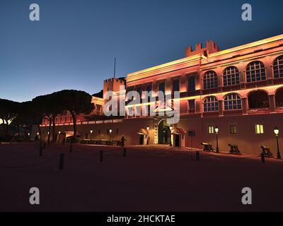 Splendida vista notturna del Palazzo del Principe Genovese di Monaco dopo il tramonto sulla Riviera Francese con facciata illuminata, cannoni e guardia pattugliante. Foto Stock