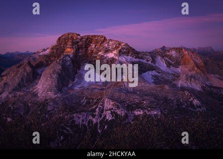 Le pareti rocciose del Monte Croda Rossa sopra Prato Piazza alp brillano viola all'alba, Dolomiti di Braies, Alto Adige, Italia Foto Stock