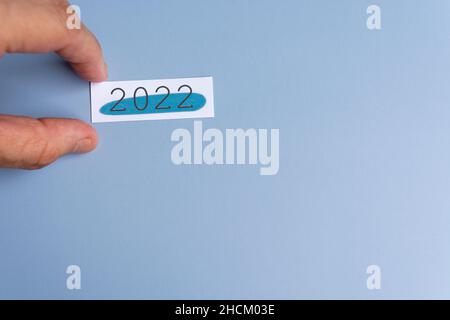 Mano che tiene un blocco note 2022 su una scrivania. Concetto di anno nuovo Foto Stock