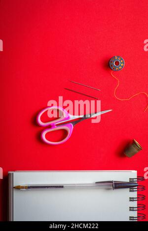 flatlay per cucire o per tessuti , su misura o fatti in casa. su sfondo rosso . Foto Stock