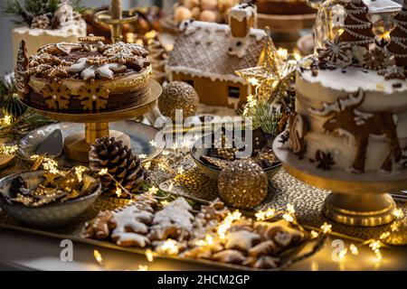 Varietà di gustosi dessert dolci appetitosi, torta con panna, cioccolato, pan di zenzero sul tavolo natalizio Foto Stock
