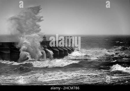 Le onde si infrangono contro il braccio del porticciolo Foto Stock