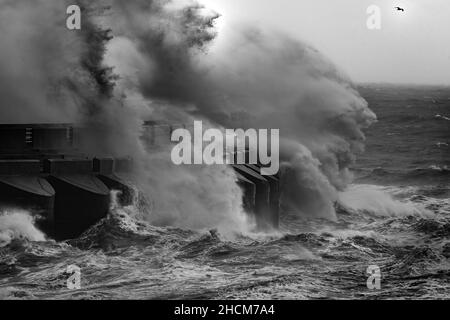 Le onde si infrangono contro il braccio del porticciolo Foto Stock