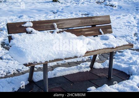 Panca in legno coperta di neve, foto di sfondo invernale. Foto Stock