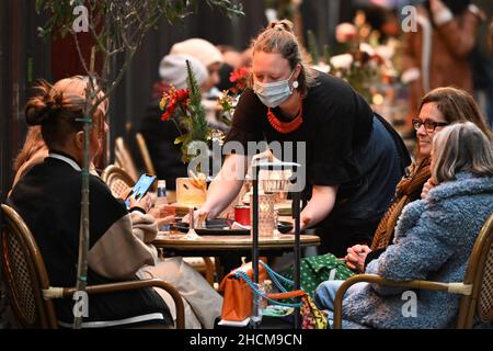 CARDIFF, GALLES - DICEMBRE 29: Un lavoratore porta un vassoio di bevande ai clienti al Cafe Barker Tea Rooms in High Street Arcade il 29 Dicembre 2021 a Cardiff, Galles. Foto Stock