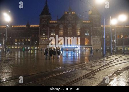 Facciata della Stazione Centrale di Amsterdam in serata in una fredda giornata di pioggia nel mese di dicembre Foto Stock