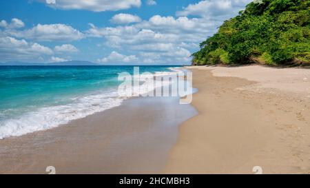 A picturesque beach scene with turquoise water, ebbing tide, wet sand, fluffy clouds, and no people. Shot in Abra de Ilog, Mindoro Island, Philippines Foto Stock