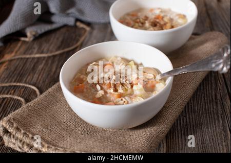 Porridge con mele cotte e patate dolci. Servito con cannella in una ciotola con cucchiaio su tavola di legno Foto Stock