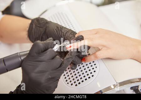 Mani manicuriste che rimuovono gommalacca dalle unghie delle donne Foto Stock