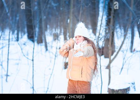 Ragazza piccola carina adolescente divertirsi giocando con le palle di neve, pronta a lanciare la palla di neve. Giochi di neve. Vacanze invernali. Foto Stock