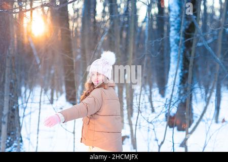 Ragazza piccola carina adolescente divertirsi giocando con le palle di neve, pronta a lanciare la palla di neve. Giochi di neve. Vacanze invernali. Foto Stock