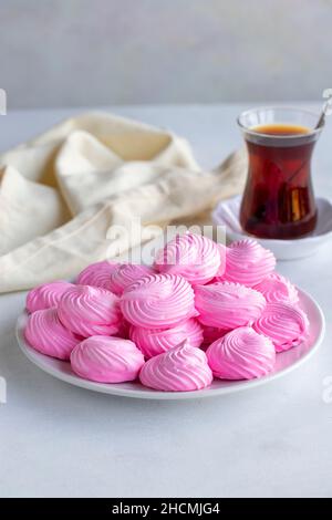 Piccoli meringui rosa in un piatto bianco. Scatto macro. Vista verticale Foto Stock