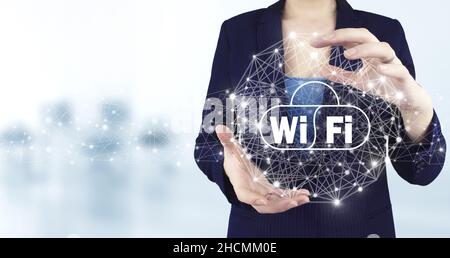 Concetto di connessione di rete aziendale e Wi-Fi in città. Icona Wi Fi olografica virtuale a due mani con sfondo sfocato chiaro. Rete Wi-Fi gratuita Foto Stock