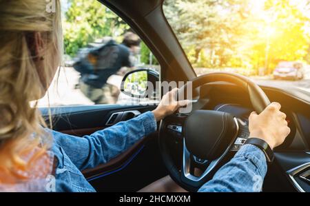Vista posteriore della giovane donna attraente in abbigliamento casual guardando con attenzione alla strada durante la guida di un'auto. Foto Stock