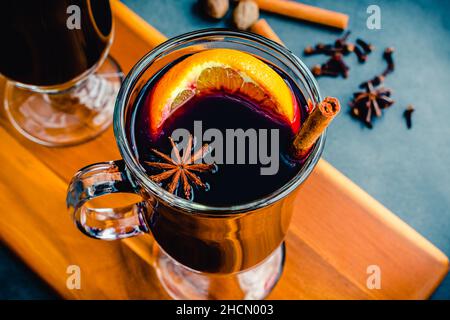 Tazze di VIN brulé guarnite con spezie intere: Vino speziato guarnito con fette d'arancia, bastoncini di cannella e anice stellato Foto Stock