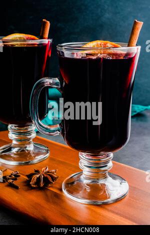 Tazze di VIN brulé guarnite con spezie intere: Vino speziato guarnito con fette d'arancia, bastoncini di cannella e anice stellato Foto Stock