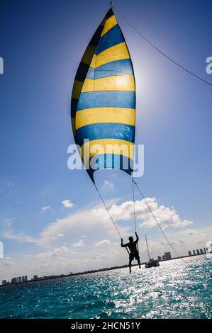 Il turista si gode il suo giro su una specie di aquilone con posto sopra il mare turchese vicino Cancun, Messico Foto Stock