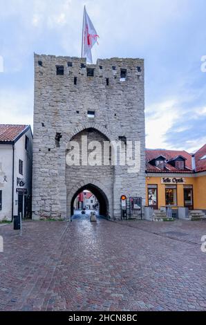 Vista esterna di Österport, (porta orientale), nelle mura medievali ben conservate della città, Visby, Gotland, Svezia, con una bandiera svedese che sventola sopra di essa Foto Stock