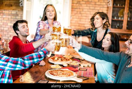 Amici gruppo bere birra e mangiare pizza al bar ristorante - concetto di amicizia con i giovani divertirsi insieme alla risto pub pizzeria Foto Stock