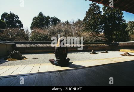 Una giovane donna (dietro di lei) sul giardino di roccia ( karesansui) Ryoan-Ji a Kyoto. Sakura (ciliegia) fiorisce! Foto Stock