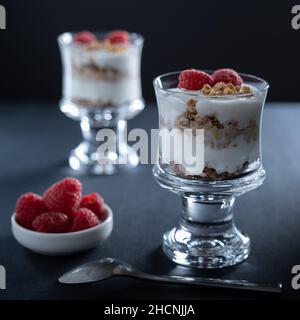 Helsinki / Finlandia - 30 DICEMBRE 2021: Due bicchieri di yogurt alla vaniglia con granola alla cannella e guarnizione di lampone Foto Stock