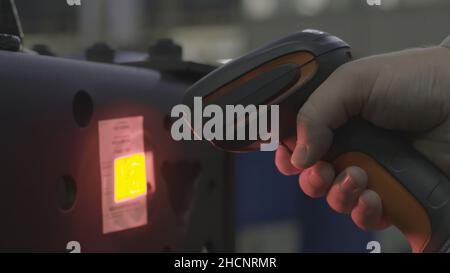 Un uomo che scansiona un codice a barre, acquista e vende concetto. Primo piano dello scanner per codici a barre con supporto manuale, scansione etichette delle confezioni con laser sulla scatola. Foto Stock