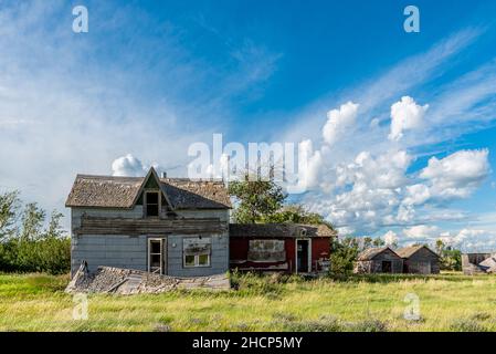 Una vecchia casa abbandonata e altri edifici sulle praterie di Saskatchewan Foto Stock