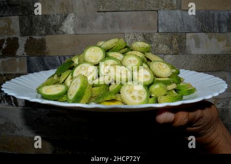 Tritata e tagliata a fette sottili di verdure indiane crude Spiny Gourds anche noto come Kantola. Preparazione per preparare gli ingredienti della ricetta Spinygourd curry Foto Stock