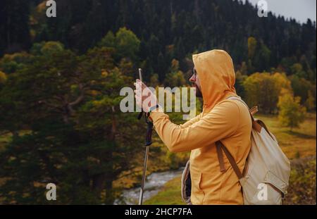 L'uomo crea splendide foto sullo smartphone per i social network. Stile di vita vagante, concetto di avventura vacanza autunnale all'aperto, da solo in natura. Viaggia verso il Caucaso settentrionale, Arkhyz, Russia Foto Stock