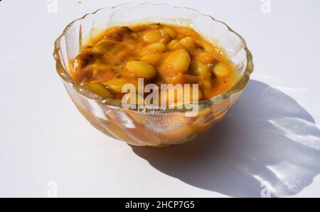 Delizioso Vaal nu shaak o bave di burro curry servito in un recipiente trasparente su sfondo bianco isolato. Gustoso curry indiano tradizionale fagioli lima o fa Foto Stock