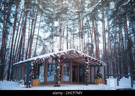 Bella casa in stile scandinavo è decorato per Capodanno e Natale, si trova in foresta. Idea e concetto di vacanze invernali in natura Foto Stock