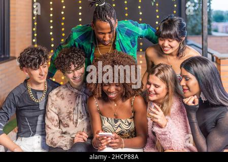 Amici multietnici che vogliono telefonare su una terrazza Foto Stock