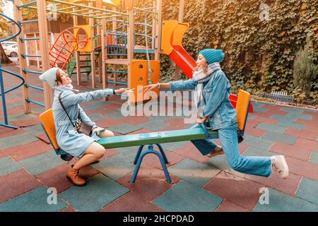 Due amiche allegre bambini o adolescenti che si divertono sulla sciabola in un parco giochi. Concetto di psicologia della nuova generazione e relazioni Foto Stock