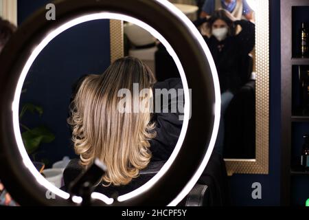 foto di capelli lunghi della donna con nuovo look nel salone del parrucchiere attraverso un cerchio chiaro Foto Stock