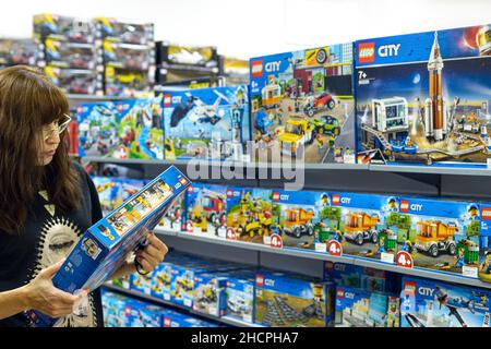 2021: Donna in un negozio Lego che detiene la serie City costruttore Lego Foto Stock