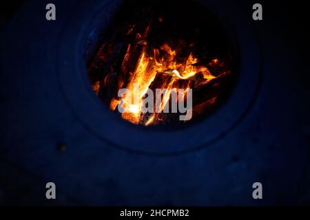 Dettagli con fuoco di legno che brucia all'interno di una stufa di ferro nel cortile di una casa rurale in Romania. Foto Stock