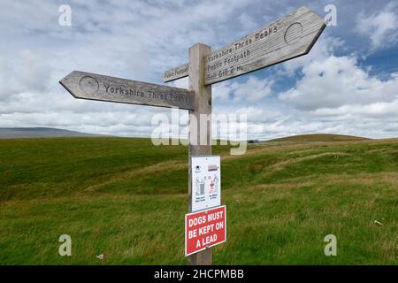 Cartello con indicazione di sentiero pubblico in legno tra Horton a Ribblesdale e Ribblehead che fornisce indicazioni per Yorkshire Three Peaks Walk Foto Stock