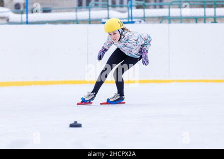 Ragazza adolescente sottile pattinare sulla pista di ghiaccio su breve treck allenamento Foto Stock