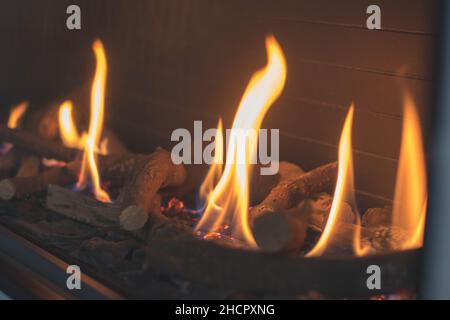 Primo piano di bastoni che bruciano in fiamme di fuoco in un camino Foto Stock