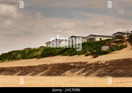 Case sul bordo di una scogliera e spiaggia con Sandscaping minacciato da erosione costiera, Bacton, Norfolk, Inghilterra Foto Stock