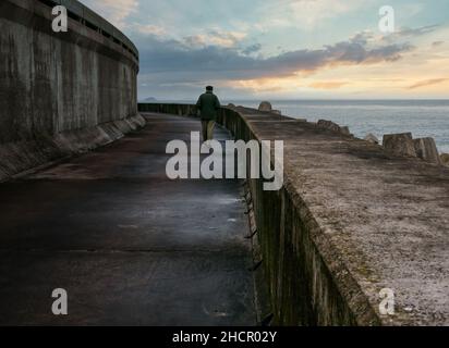 Uomo che cammina sulla passerella di cemento del perimetro della centrale nucleare di Torness, East Lothian, Scozia, Regno Unito Foto Stock