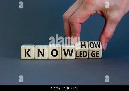 Simbolo di conoscenza e know-how. L'uomo d'affari trasforma i cubi, cambia la parola know-how in conoscenza. Bellissimo sfondo grigio, spazio di copia. Affari, conoscenza Foto Stock