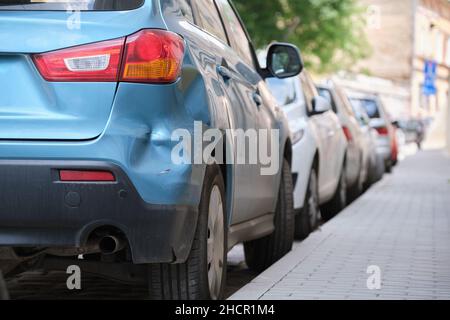 Auto ammaccata con parafango danneggiato parcheggiato sul lato della strada. Sicurezza stradale e concetto di assicurazione del veicolo. Foto Stock