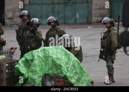 Hebron. 31st Dic 2021. Un soldato israeliano punta la sua arma contro i manifestanti palestinesi durante gli scontri a seguito di una protesta contro l'espansione degli insediamenti ebraici nella città di Hebron, in Cisgiordania, 31 dicembre 2021. Credit: Mamoun Wazwaz/Xinhua/Alamy Live News Foto Stock