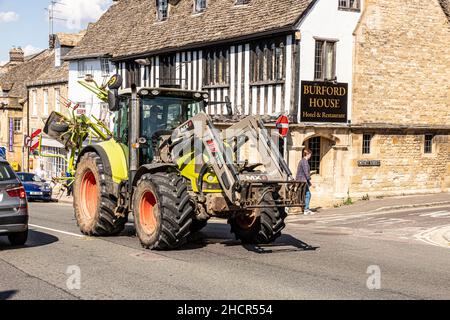 Grandi macchine agricole che guidano nella High Street della città Cotswold di Burford, Oxfordshire Regno Unito Foto Stock