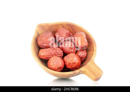 Diverse bacche di ziziphus secche con un piatto di legno, primo piano, isolato su bianco. Foto Stock