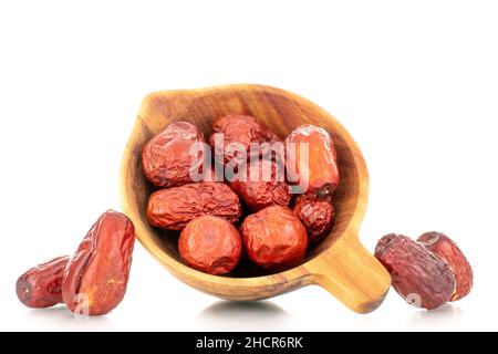 Diverse bacche di ziziphus secche con un piatto di legno, primo piano, isolato su bianco. Foto Stock