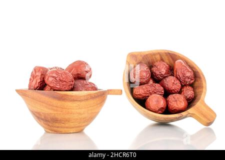 Diverse bacche di ziziphus secche con un piatto di legno, primo piano, isolato su bianco. Foto Stock